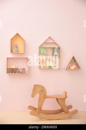 Elegante design interno della stanza del bambino con mensole a forma di casa e cavallo a dondolo Foto Stock