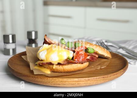 Delizioso uovo Benedict servito su piatto di legno Foto Stock
