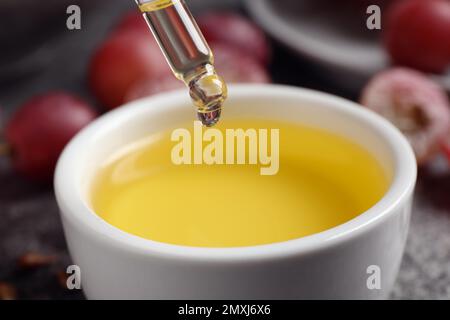 Gocciolamento di olio di semi d'uva naturale in ciotola, primo piano. Cosmetico organico Foto Stock