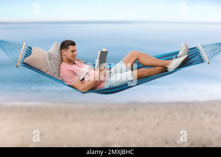 Uomo che legge libro in amaca vicino al mare nelle giornate di sole Foto Stock