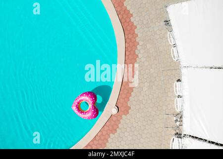 Anello gonfiabile a forma di cuore galleggiante in piscina, vista dall'alto. Vacanze estive Foto Stock