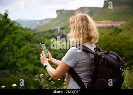 Donna escursionista utilizza gps navigatore app in smartphone a piedi in montagna, persona turistica guardare il telefono cellulare per la navigazione. Concetto di escursioni, natura, j Foto Stock