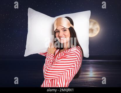 Bella donna che tiene cuscino e notte cielo stellato con luna piena sullo sfondo. Ora di coricarsi Foto Stock