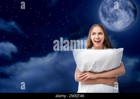 Bella donna che tiene cuscino e notte cielo stellato con luna piena sullo sfondo. Ora di coricarsi Foto Stock