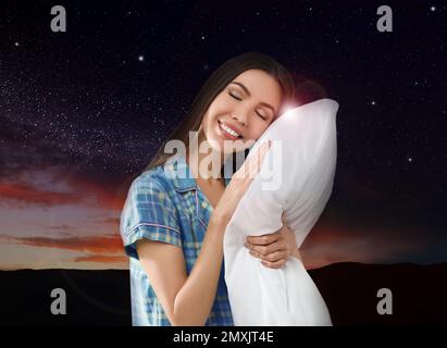 Bella donna che tiene il cuscino, cielo stellato notte sullo sfondo. Ora di coricarsi Foto Stock