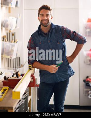 Se il suo rotto Ill ripararlo. Ritratto di un bel giovane handyman in piedi davanti ai suoi utensili da lavoro. Foto Stock