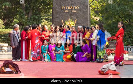 Un grande gruppo di donne per lo più vietnamite vestite di colorato tradizionale ao dai, si organizzano per posarsi per una foto di gruppo nel centro di Hanoi, Vietn Foto Stock