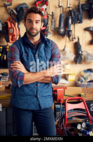 La mia officina, a modo mio. Ritratto di un bel giovane handyman in piedi davanti ai suoi utensili da lavoro. Foto Stock