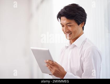 Ha sempre accesso a dati importanti. un bell'uomo d'affari asiatico che utilizza il suo tablet digitale in ufficio. Foto Stock