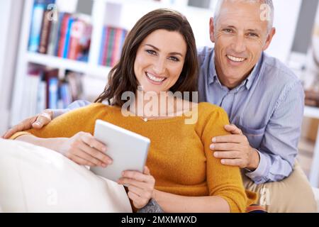 Questo è il modo in cui ci teniamo in contatto con il resto della famiglia. un uomo maturo e la moglie più giovane usano un tablet insieme a casa. Foto Stock