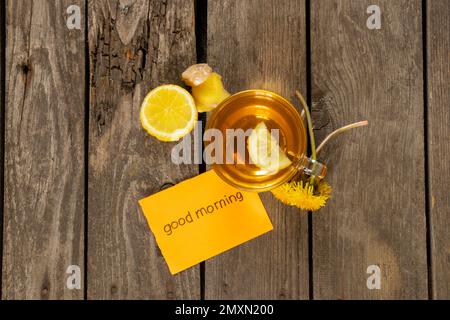 Una tazza di tè con dente di limone e le parole in inglese buon mattino Foto Stock