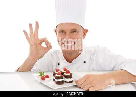 Chef perfetto, segno e dessert felice con piatto o sapore di cioccolato dolce con gesto mano isolato in studio sfondo bianco. Ritratto, sorriso e. Foto Stock