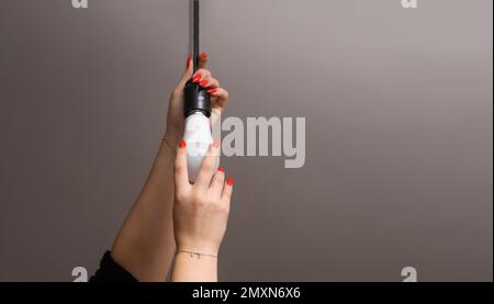 le mani femmina si avvitano nella lampada. Foto di alta qualità Foto Stock