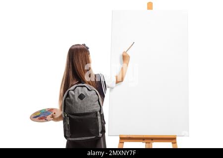 Schoolgirl pittura su una tela con un pennello e tavolozza isolato su sfondo bianco Foto Stock