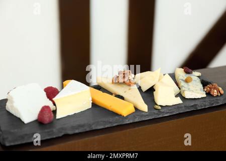 Diversi tipi di deliziosi formaggi e snack su piatto di ardesia Foto Stock