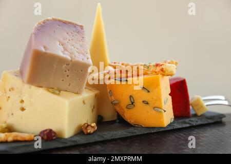 Diversi deliziosi formaggi su piatto di ardesia, primo piano Foto Stock