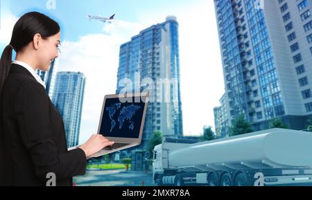 Concetto logistico. Donna d'affari che utilizza un computer portatile con mappa del mondo. Camion, aereo ed edifici sullo sfondo, di colore blu Foto Stock