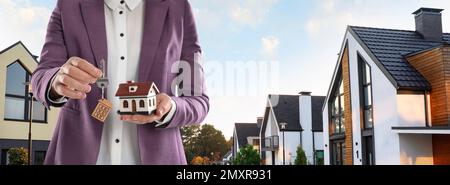 Agente immobiliare con modello contro le case moderne, spazio per il testo. Banner design, primo piano Foto Stock