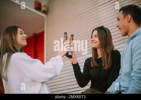 Primo piano di due ragazze che fanno il tifo con la birra in piedi con la loro prima estremità Foto Stock