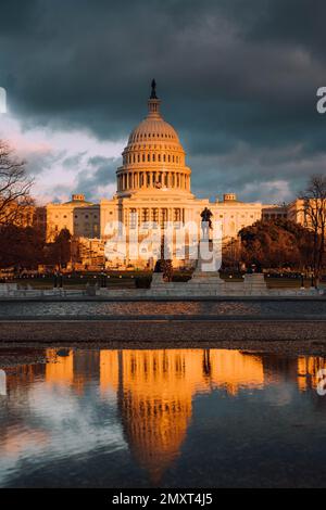 Il tramonto d'oro che cade sul Campidoglio degli Stati Uniti a Washington contro il cielo nuvoloso Foto Stock