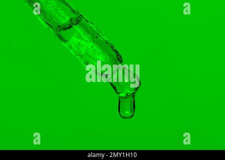 Pipetta cosmetica con liquido gocciolante, olio e gocce su sfondo verde, siero, siero, gel, vitamina, acqua, olio. Cosmetici naturali Foto Stock