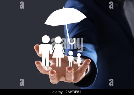 Concetto assicurativo - ombrello dimostrante protezione. Uomo con illustrazioni su sfondo scuro, primo piano Foto Stock