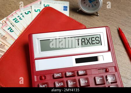 Calcolatrice con tasse di parola, notebook e denaro sul tavolo, primo piano Foto Stock