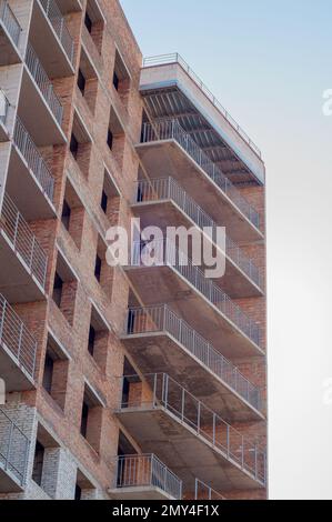 Un edificio residenziale a più piani in costruzione, un frammento di una casa. Pareti in mattoni, solette monolitiche in cemento, finestre vuote e balconi Foto Stock