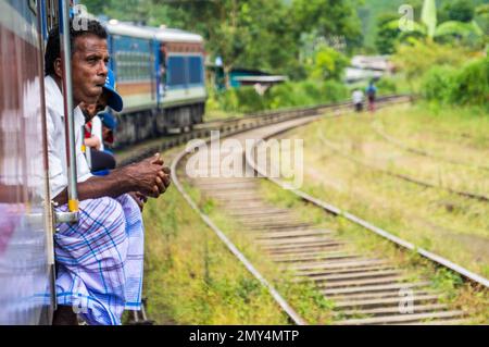 Un uomo che guarda penosamente dal treno attraverso la Hill Country da Kandy ad Ella. Sri Lanka Foto Stock