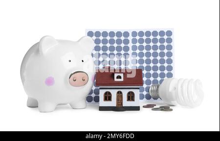 Composizione con pannelli solari e piggy bank su sfondo bianco Foto Stock