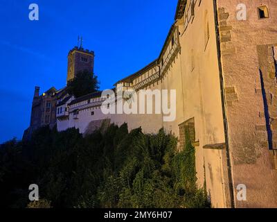 Eisenach, Germania - 09 06 2021: Il vecchio castello tedesco di Wartburg di Eisenach illuminato di notte, torreggiante sopra la città vecchia, era il rifugio del p Foto Stock