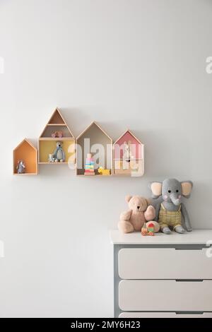 Scaffali a forma di casa e cassettiera con giocattoli nella stanza dei bambini. Design degli interni Foto Stock