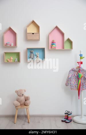 Elegante design interno della stanza del bambino con ripiani a forma di casa e appendiabiti Foto Stock