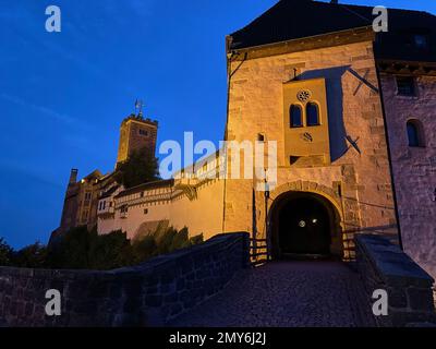 Eisenach, Germania - 09 06 2021: Il vecchio castello tedesco di Wartburg di Eisenach illuminato di notte, torreggiante sopra la città vecchia, era il rifugio del p Foto Stock