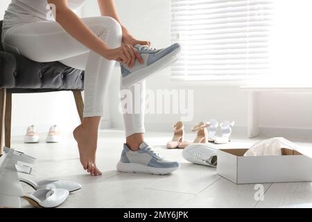 Giovane donna che prova le scarpe in casa, primo piano Foto Stock