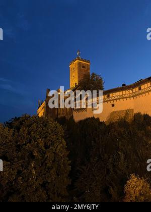 Eisenach, Germania - 09 06 2021: Il vecchio castello tedesco di Wartburg di Eisenach illuminato di notte, torreggiante sopra la città vecchia, era il rifugio del p Foto Stock