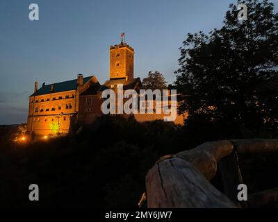 Eisenach, Germania - 09 06 2021: Il vecchio castello tedesco di Wartburg di Eisenach illuminato di notte, torreggiante sopra la città vecchia, era il rifugio del p Foto Stock