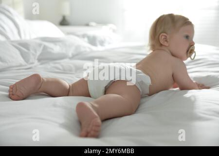 Cute bambino piccolo in pannolino in camera da letto, fuoco sulle gambe Foto Stock