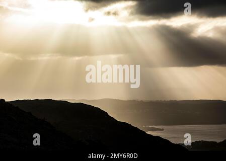 La splendida vista panoramica dell'alba invernale da Loughrigg è caduta in direzione di Windermere con splendidi raggi di sole provenienti dalle nuvole scure Foto Stock