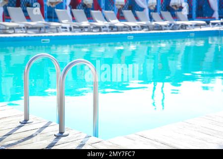 Scala con barre di appoggio nella piscina esterna Foto Stock