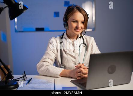Medico di sesso femminile che parla con colleghi o pazienti attraverso una videochiamata con un computer portatile durante la consultazione. Concetto online medico. Foto Stock