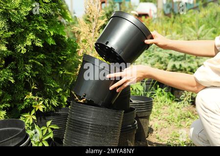 Donna con vasi neri per piantare alberi all'aperto, primo piano Foto Stock