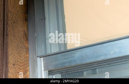 Una vecchia casa ha bisogno di qualche lavoro di riparazione professionale come questa finestra rotta e vetro ingiallito mostra. La vecchia casa poteva usare un falegname, maintena Foto Stock