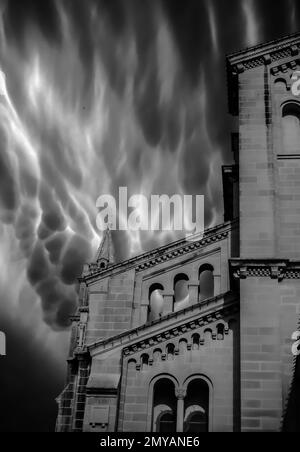 Un affascinante scatto verticale di una scala di grigi monocromatica di un pinnacolo di una chiesa in una giornata tempestosa Foto Stock