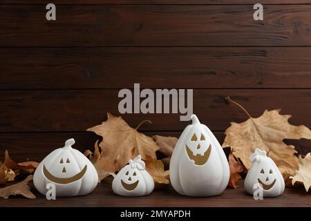 Portacandele a forma di zucca bianca e foglie asciutte su tavolo di legno. Decorazione di Halloween Foto Stock