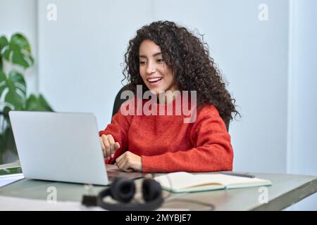 Felice sorpresa giovane donna di affari latina che guarda il portatile. Foto Stock