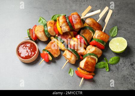 Deliziosi kebab di pollo con verdure e ketchup sul tavolo grigio Foto Stock