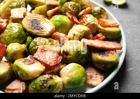 Deliziosi germogli di Bruxelles fritti con pancetta sul tavolo, primo piano Foto Stock