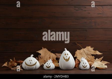 Portacandele a forma di zucca bianca e foglie asciutte su tavolo di legno. Decorazione di Halloween Foto Stock