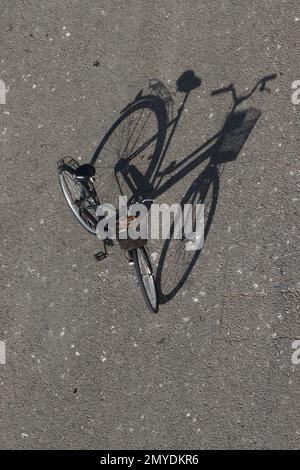 La luce del sole della sera getta una lunga ombra unica da una bicicletta da donna parcheggiata sul molo di Zara, Croazia, 2022 settembre. Foto Stock